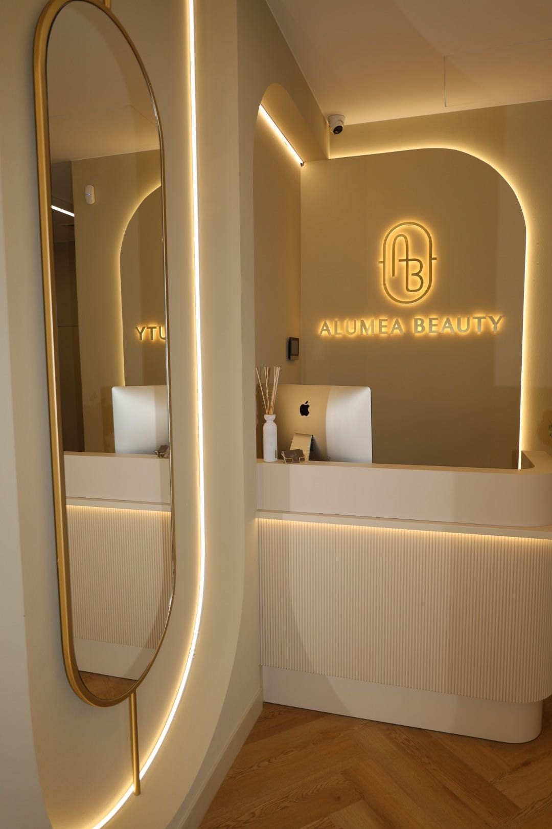 Recepcja: owalne lustro w mosiężnej ramie, podświetlony łuk i neon Alumea Beauty